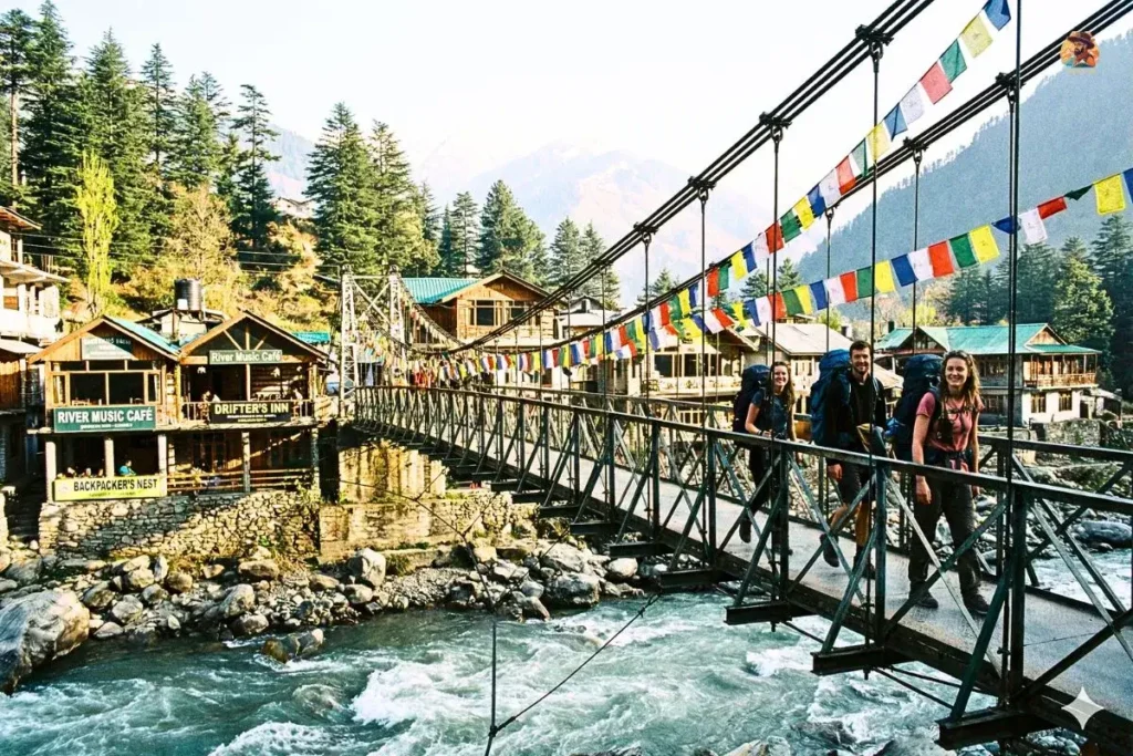 Old Manali bridge with river, cafés, and backpacker lanes